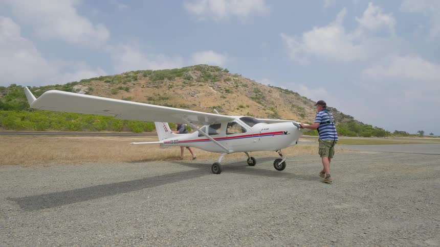 Two men push a plane on the runway