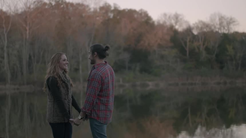 A man and a woman hold hands near a pond