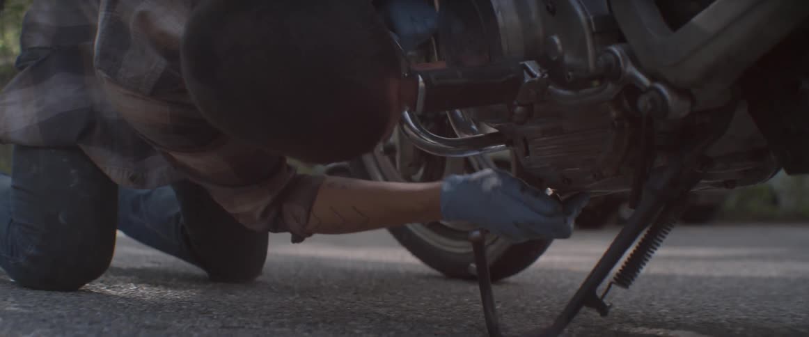 A man is using a socket wrench on a motorcycle