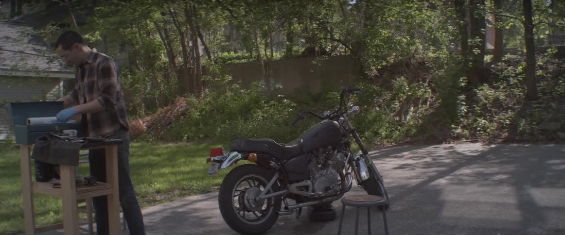 A man works outside next to a motorcycle