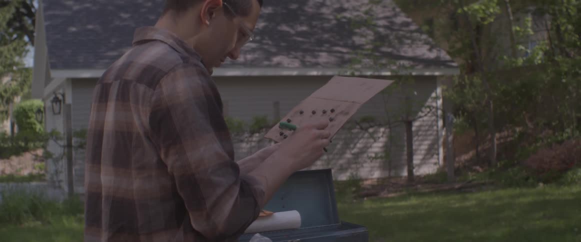 A man writes on and examines a piece of cardboard