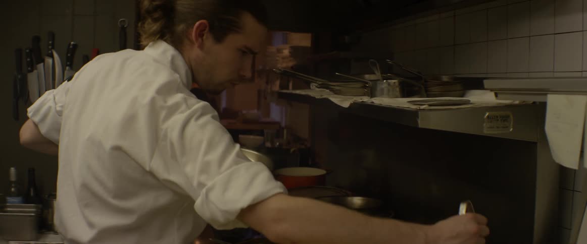 A chef is cooking on a stove top in a kitchen