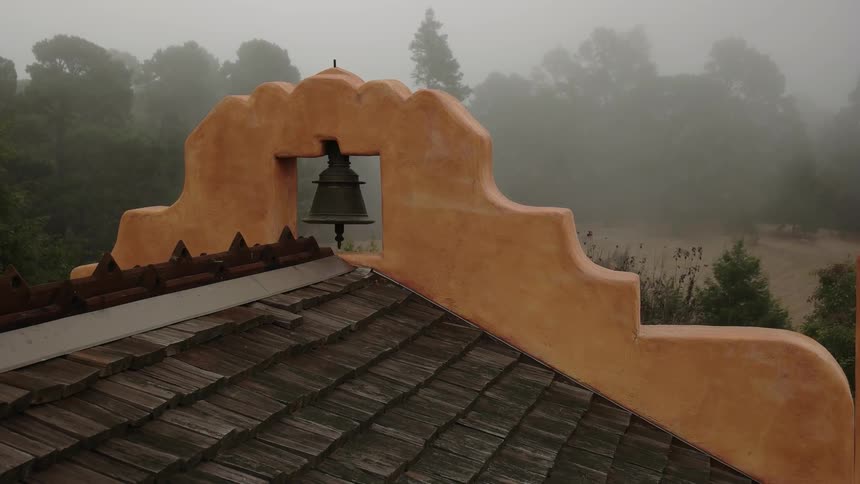 Fog hangs in the air around a building with a bell