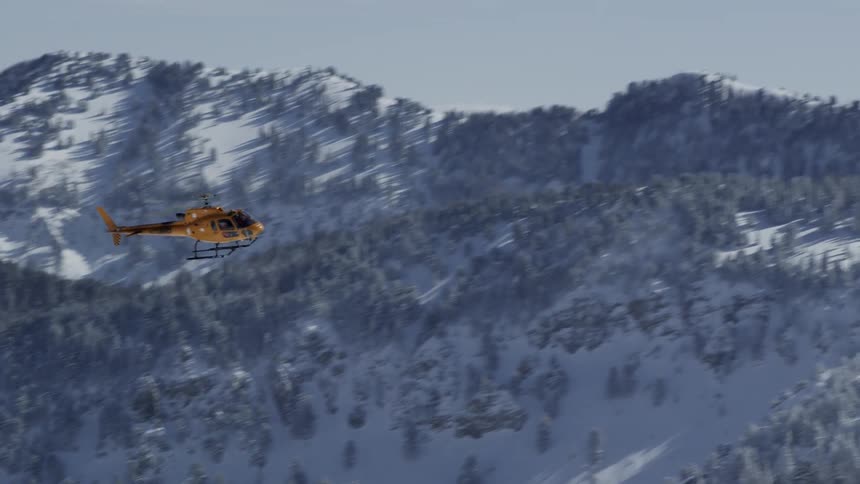 A helicopter flies over a mountain range