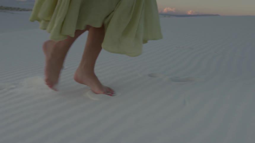 Woman walks barefoot across the desert