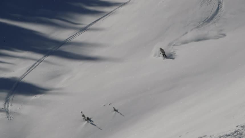 A skier speeds down a snowy mountainside