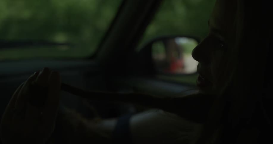 A woman twirls her hair while riding in a car