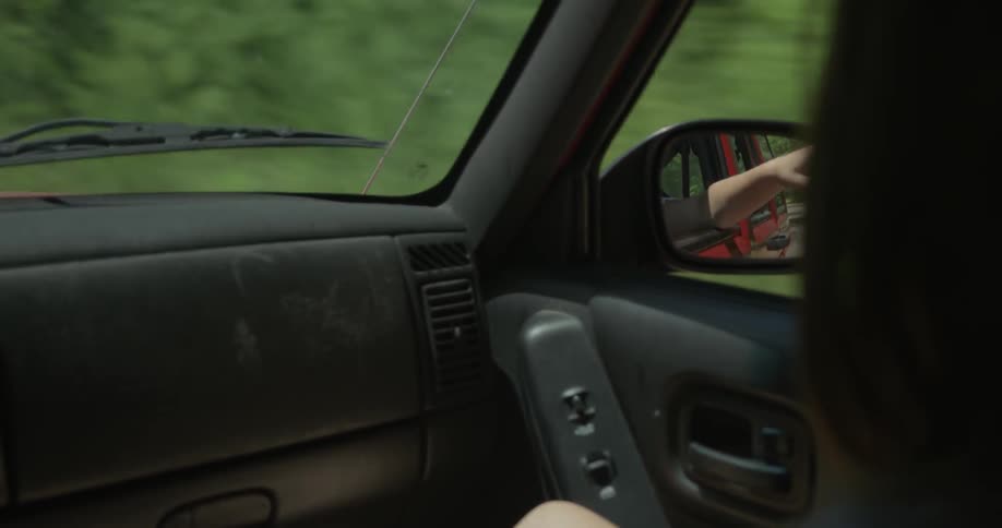 A person hangs their hand out the window as they drive