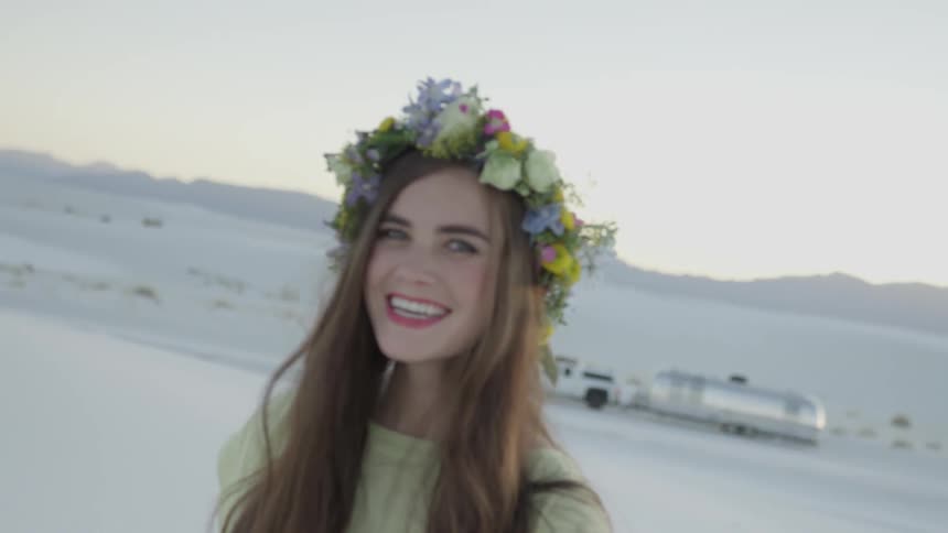 A woman standing in a desert smiles as she looks at the camera