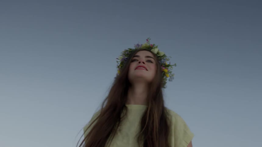 A woman is smiling with a flower wreath on her head