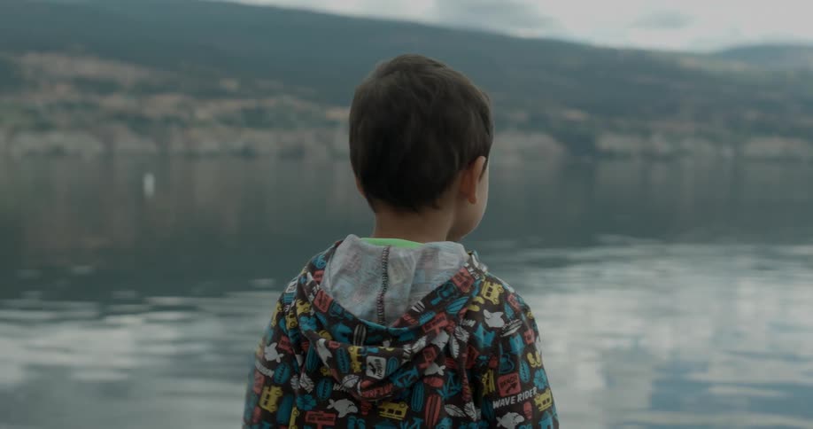 A boy points at something out in the water