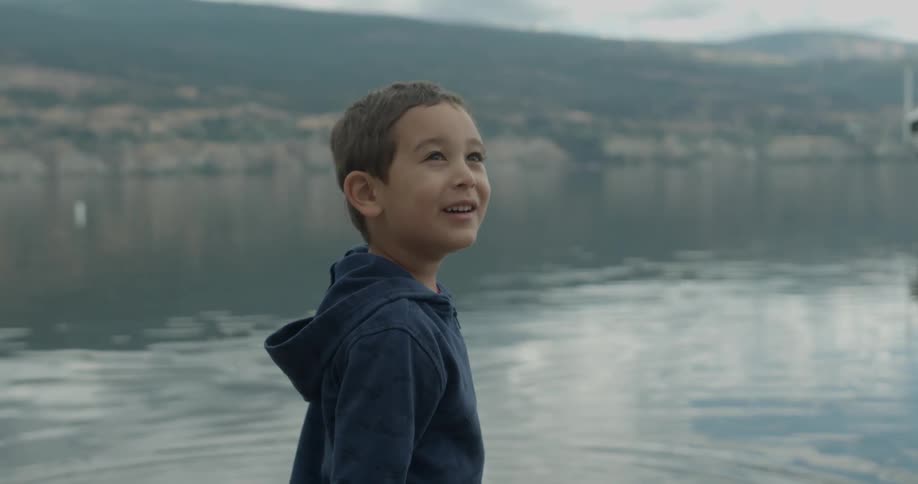 A boy turns from the lake smiling