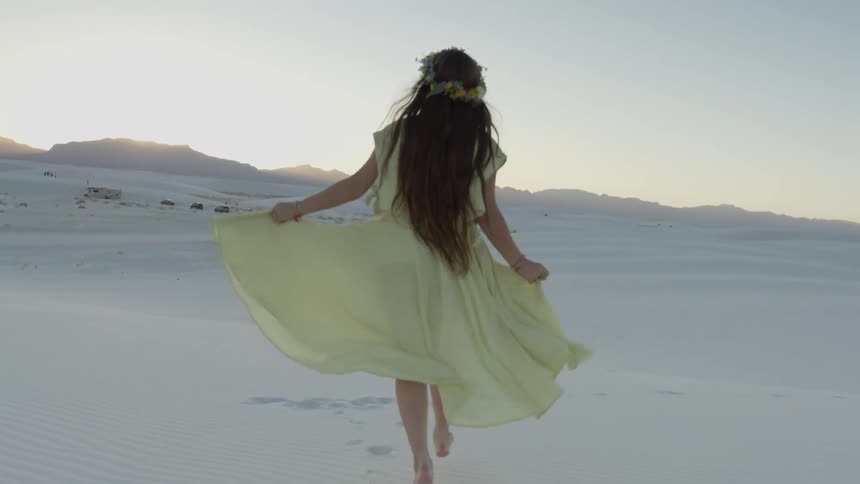A woman runs in a desert at sunset
