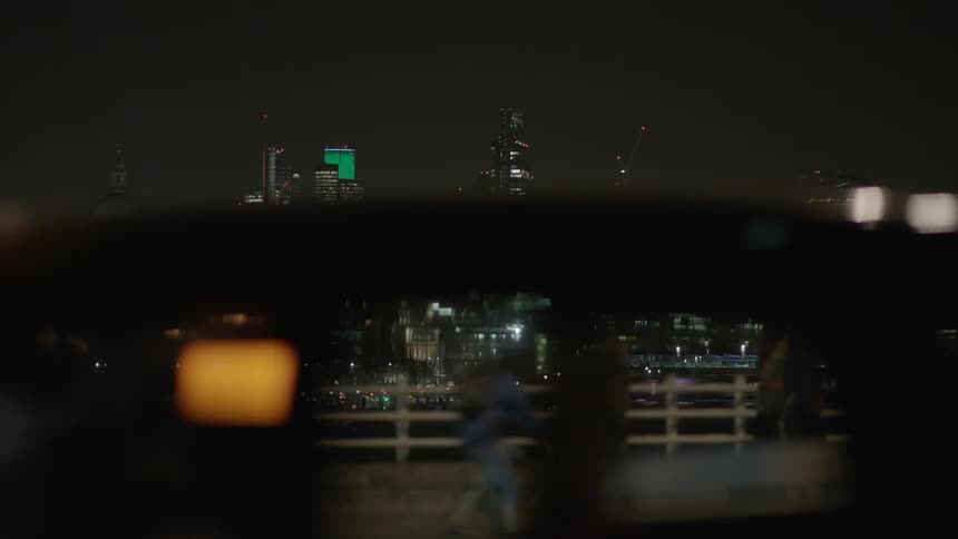 Cars and pedestrians travel on a city bridge at night
