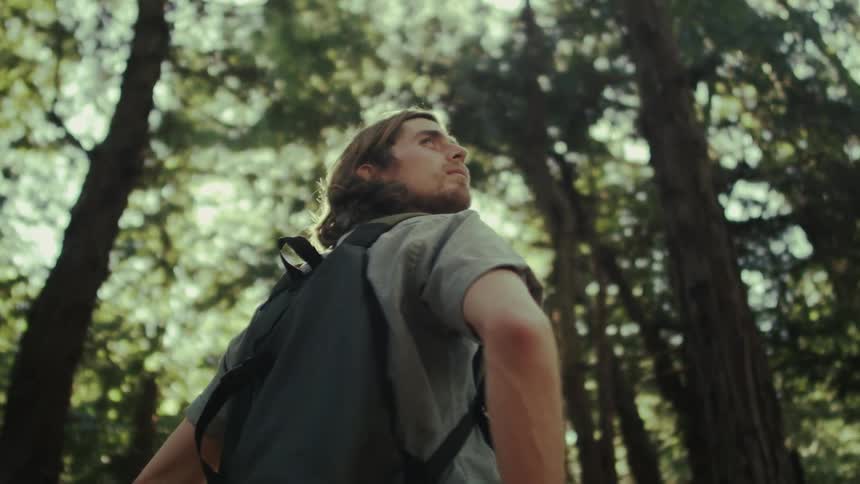 Man wearing a backpack in nature looks up