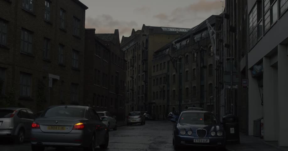 A car drives on a city street at dusk
