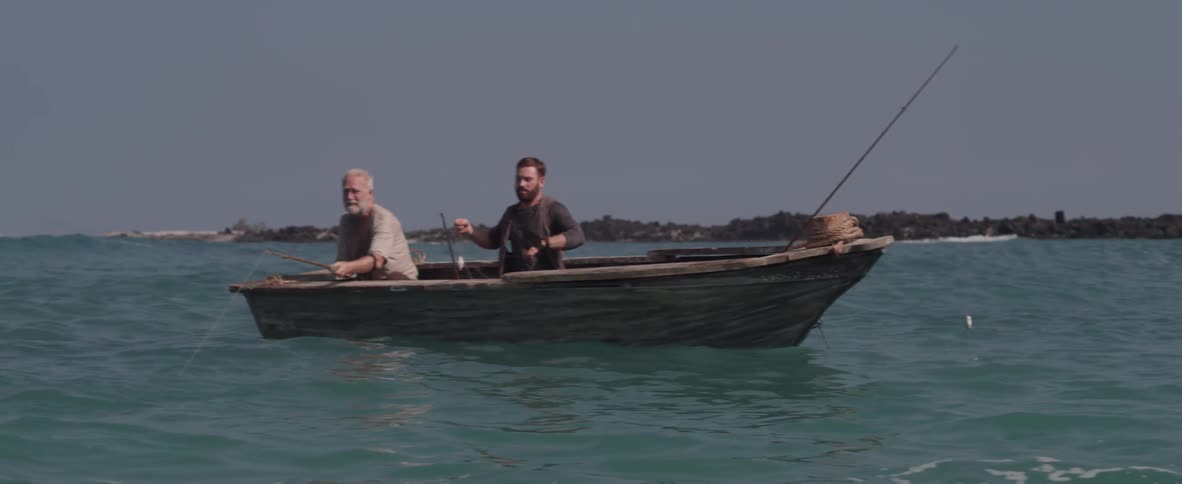 Two men fish on a boat together