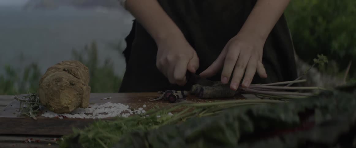 A girl cuts vegetables outside on a cutting board