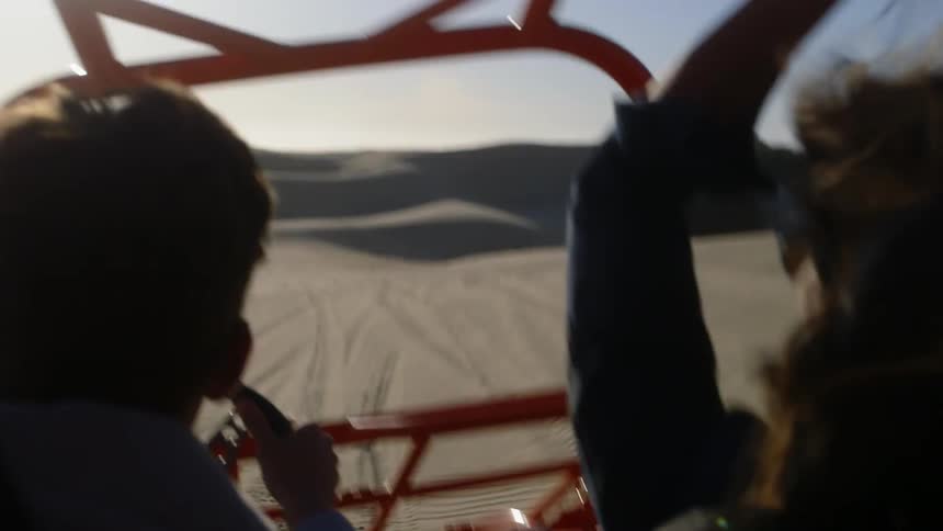 Two people ride a buggy in the desert