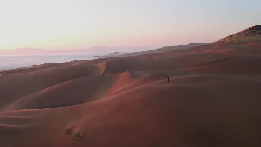 A person hikes on the sand dunes