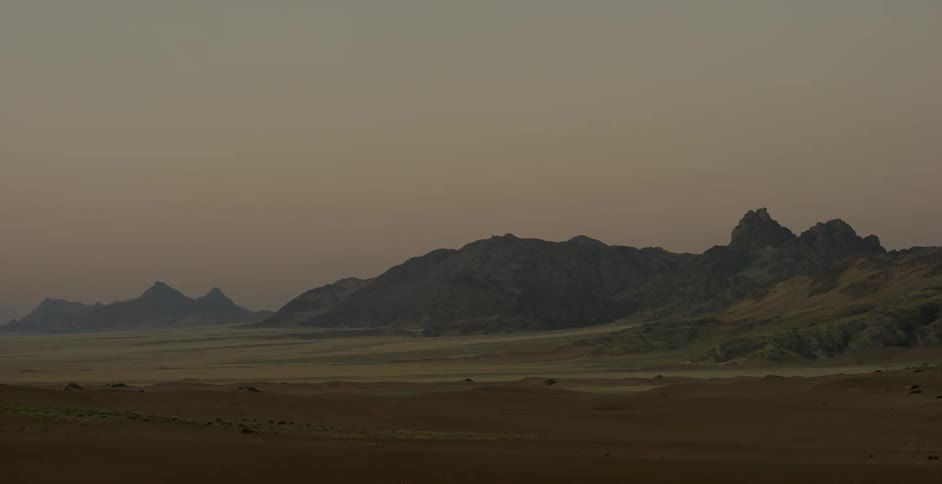 A valley with mountains beyond are being filmed