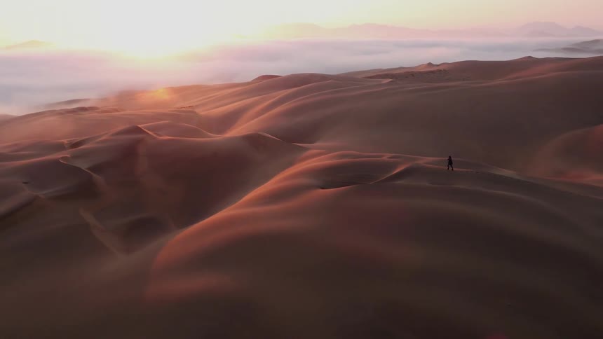 A man is running across the dunes of the desert