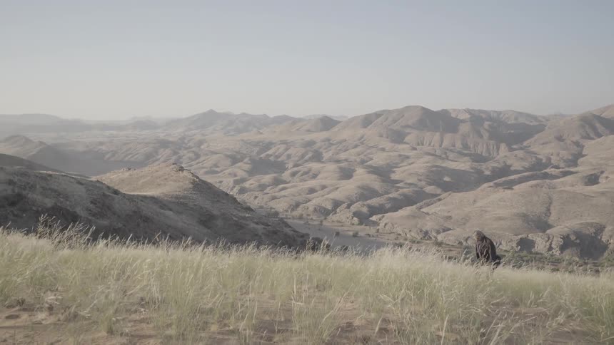A man hikes in the mountains on a sunny day