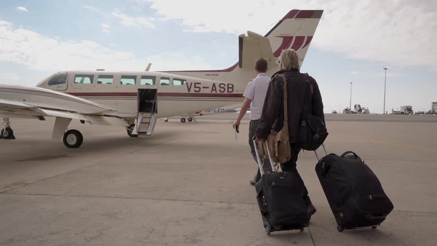 Two people are walking towards a small plan on the runway