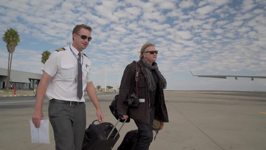 Two men walk towards a plane together