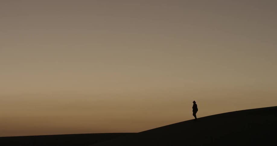 A man walks along a ridge at sunset