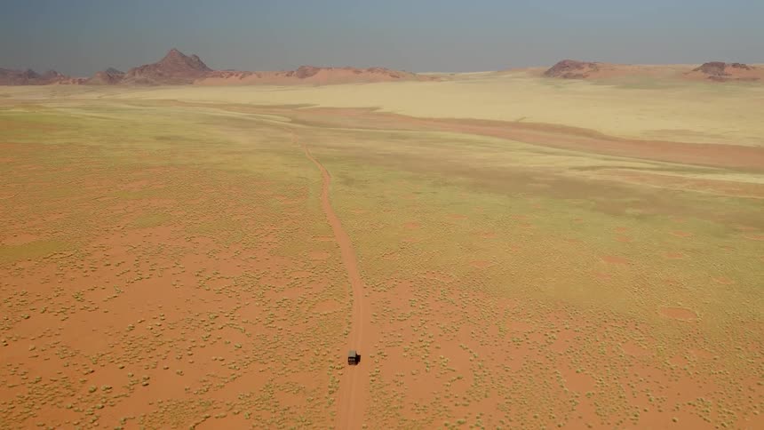 A vehicle drives on a dirt road in the wilderness