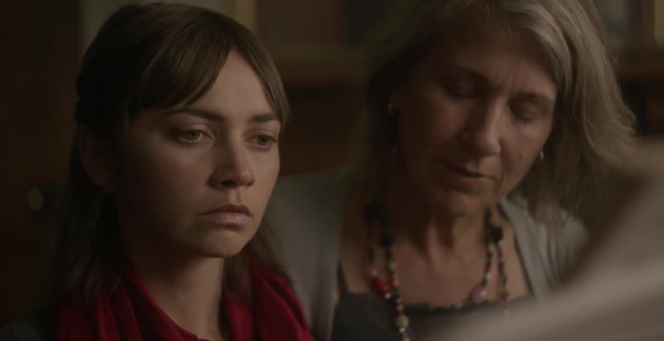 Two women sit together listening to something