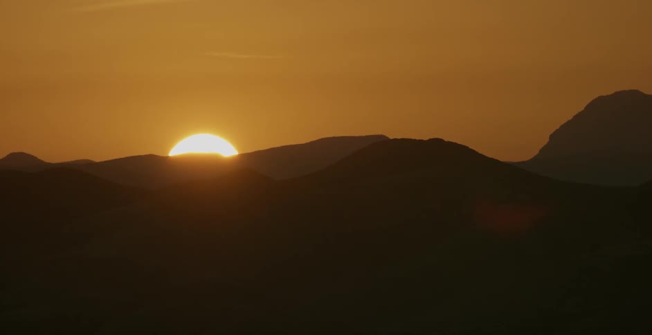 The sun slowly sets behind the mountain