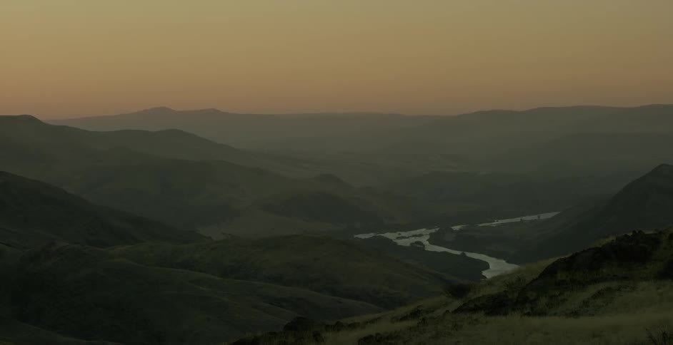 A river runs through the mountains at sunset