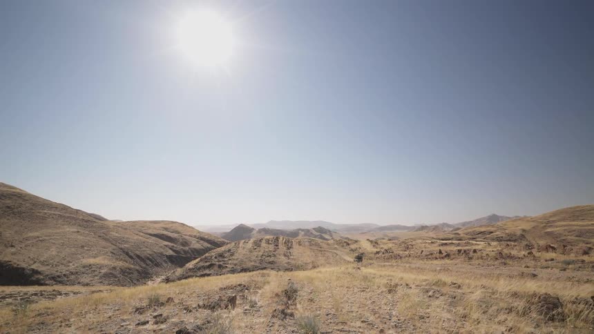 A rocky dusty desert is filmed in the midday sun