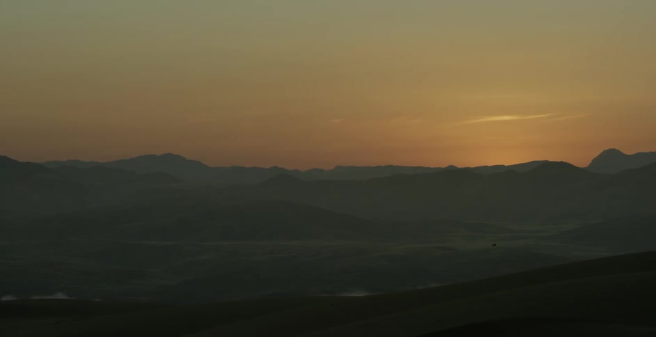 The sun sets over hills and ridges