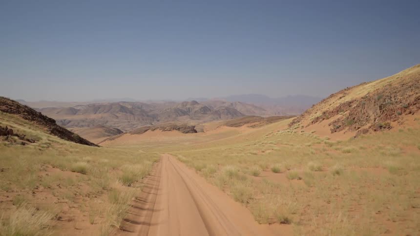 Traveling view going down a dirt road near mountains