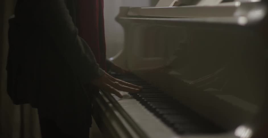 A woman plays a piano while standing up