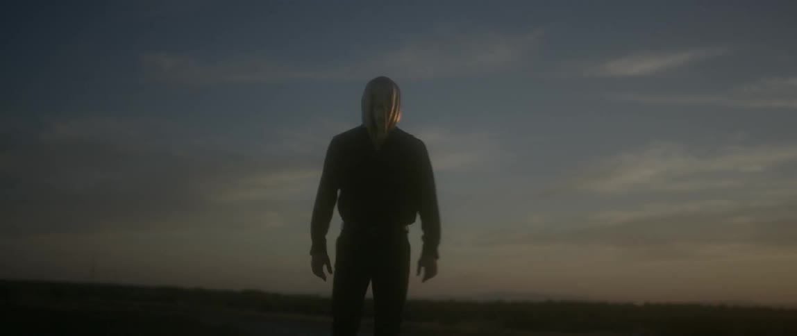 A man is hiking in the desert wearing a gold hood