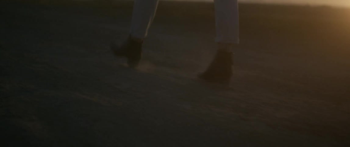 A woman's boots at she walks outside at sunset