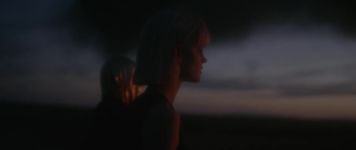 A woman and a hooded figure stand and stare