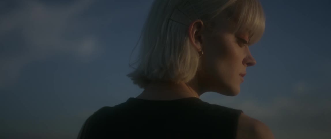A woman stands outside at sunset