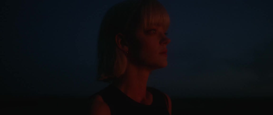 A fire illuminates a woman's face outside at night