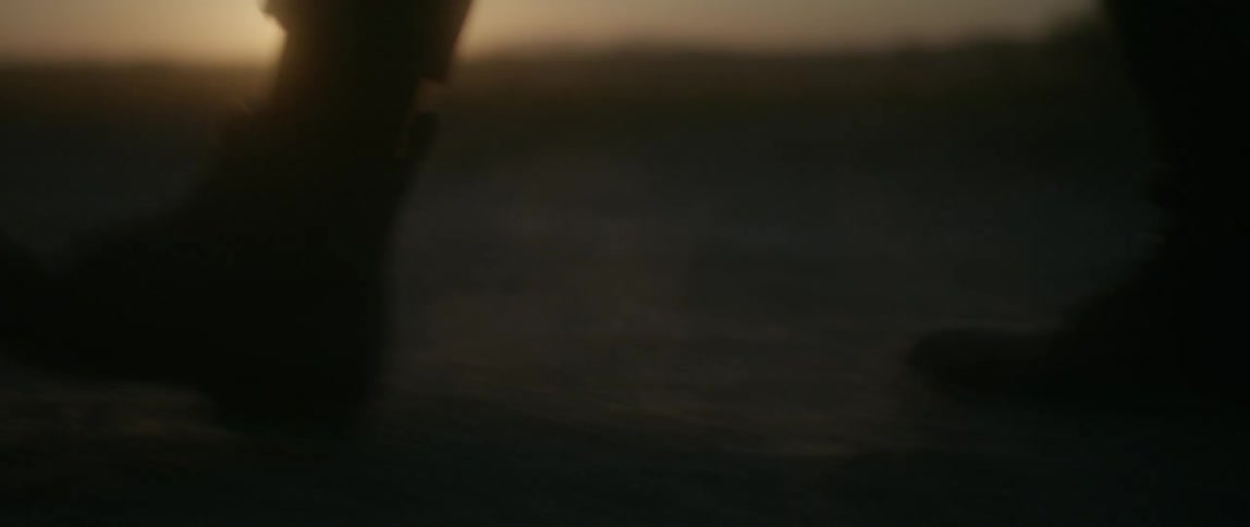 A person walks on the field as the sun sets