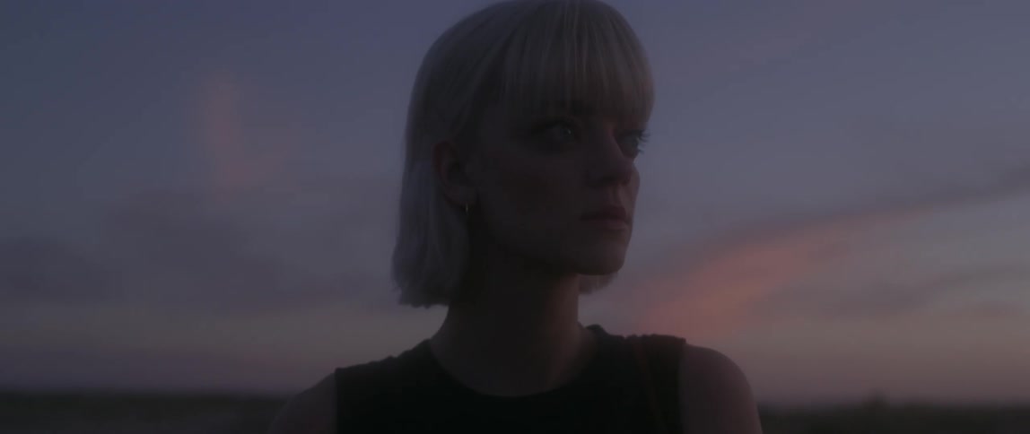 A woman standing outside looks up at something