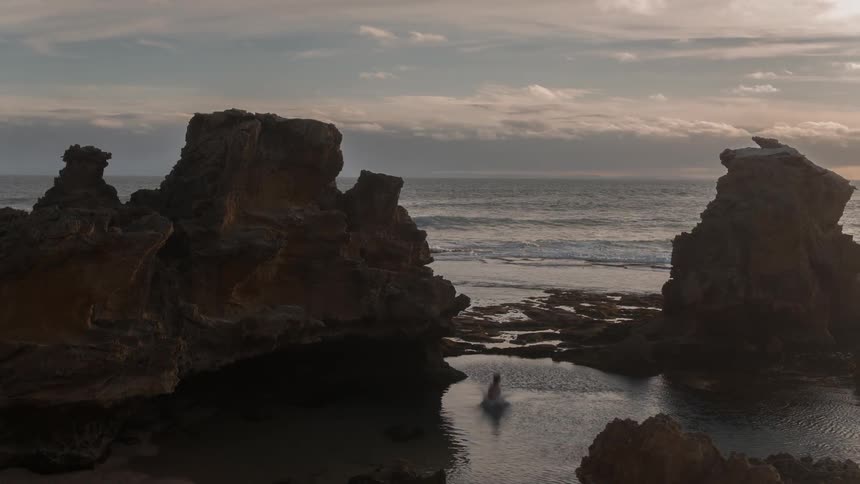 A man runs off the edge of a cliff landing in the water