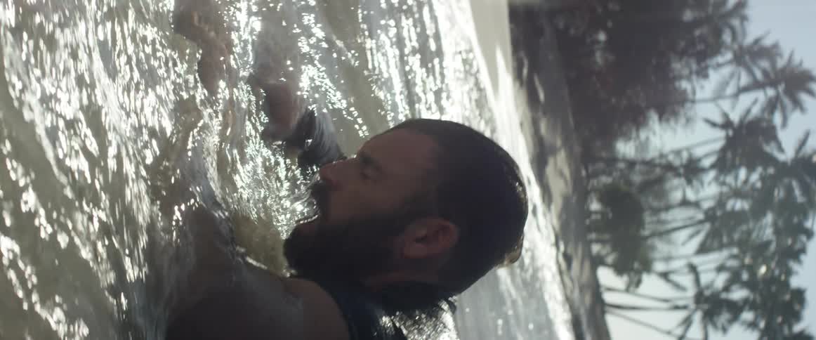 An unconscious man is roused by waves washing over him