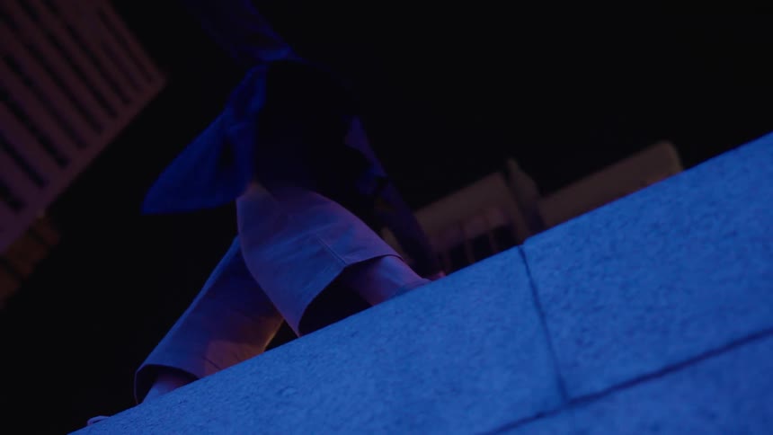 A woman balances on a concrete wall at night