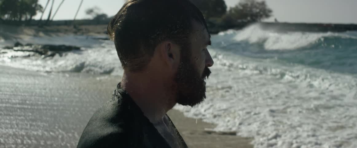 A man stands near the water looking forward