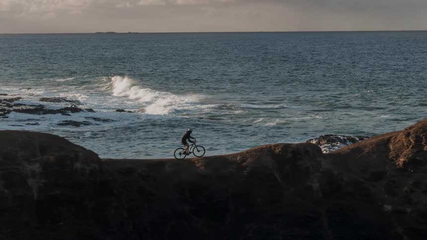 A person is riding their bike along a cliff next to the ocean